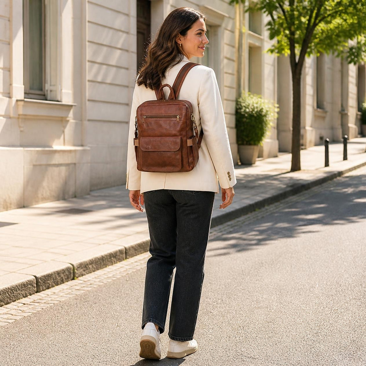 Woman wearing the DEKVIO 16 inch brown leather backpack on a sunlit street