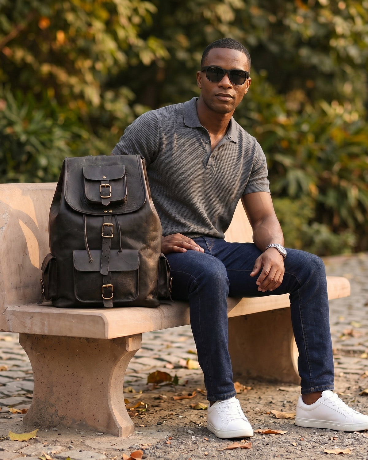 Man seated on a bench with the DEKVIO 20 inch black leather backpack