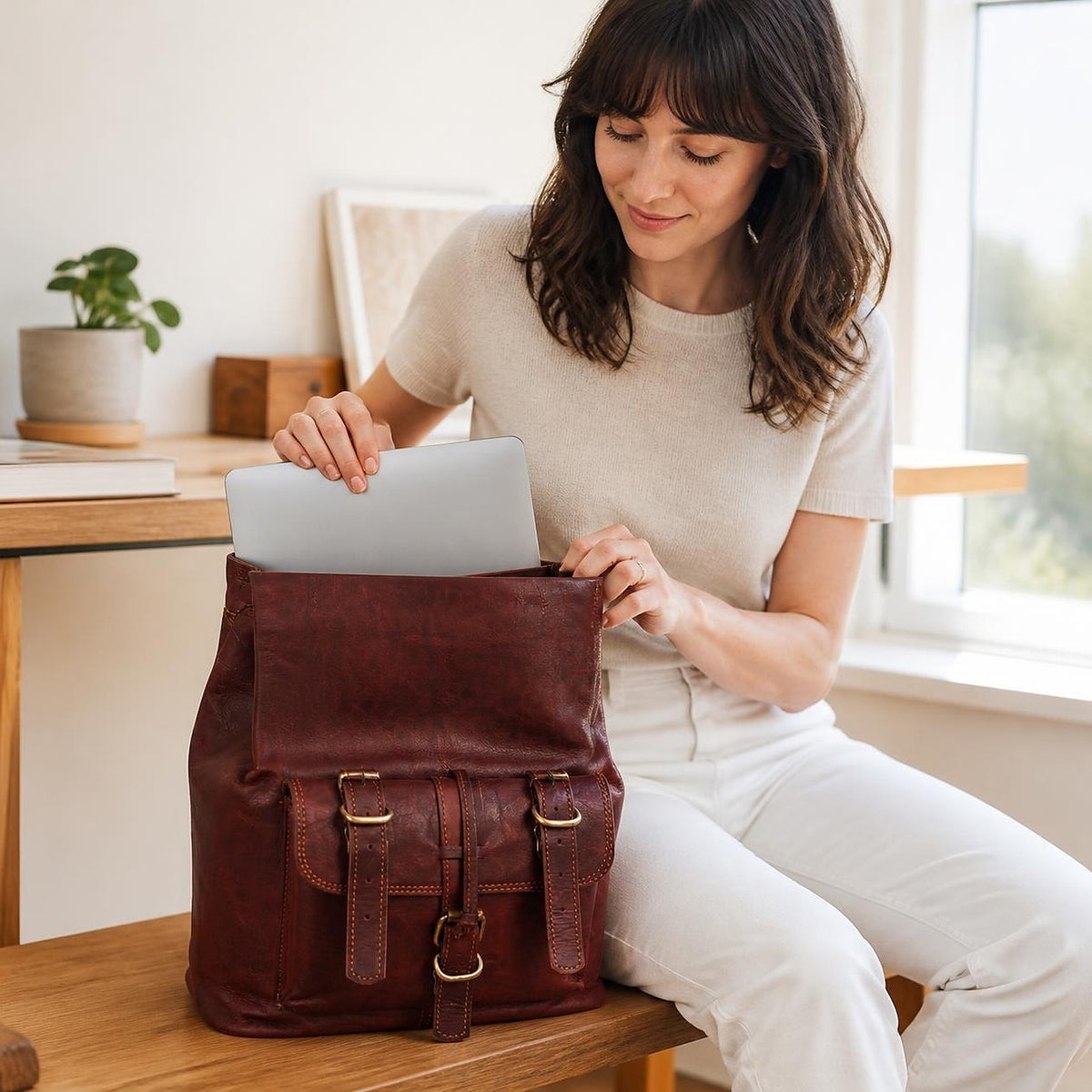 A laptop going into the DEKVIO Explorer leather backpack